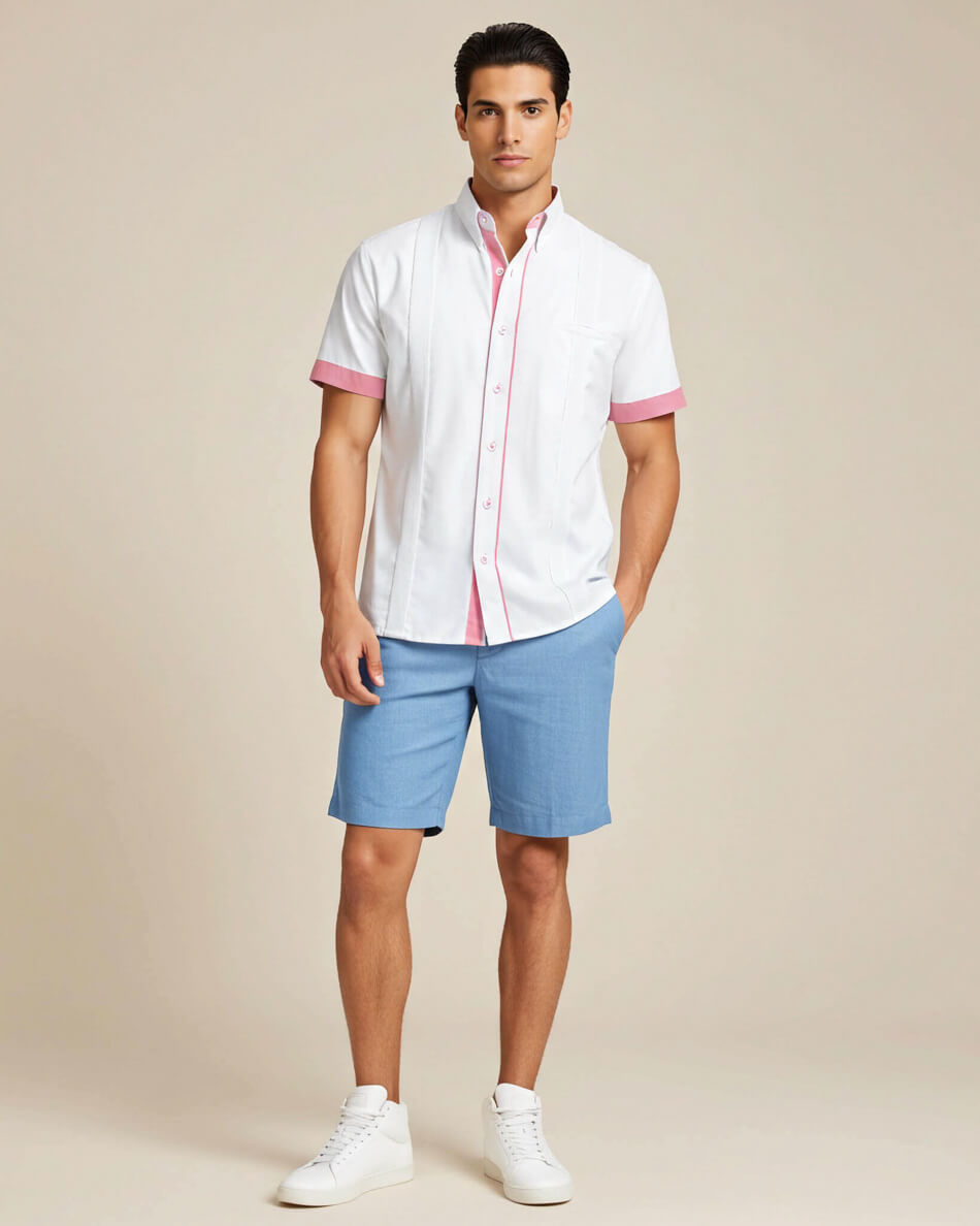 Man wearing a white guayabera shirt with pink accents and blue shorts on a beige background