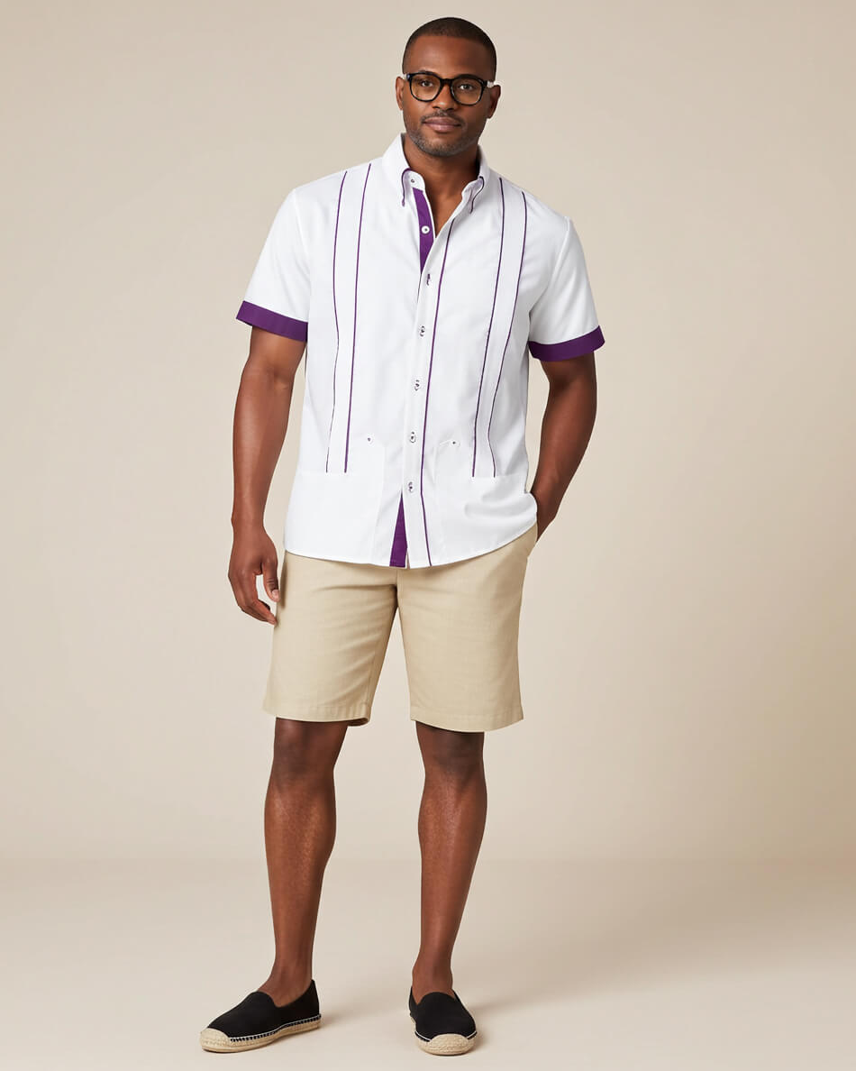 Man wearing a white guayabera shirt with purple accents and beige shorts on a beige background