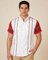 Man wearing a white guayabera shirt with colorful striped sleeves on a beige background