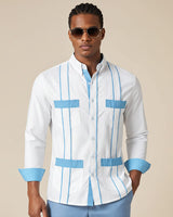 Man wearing a white guayabera shirt with blue accents and sunglasses on a beige background