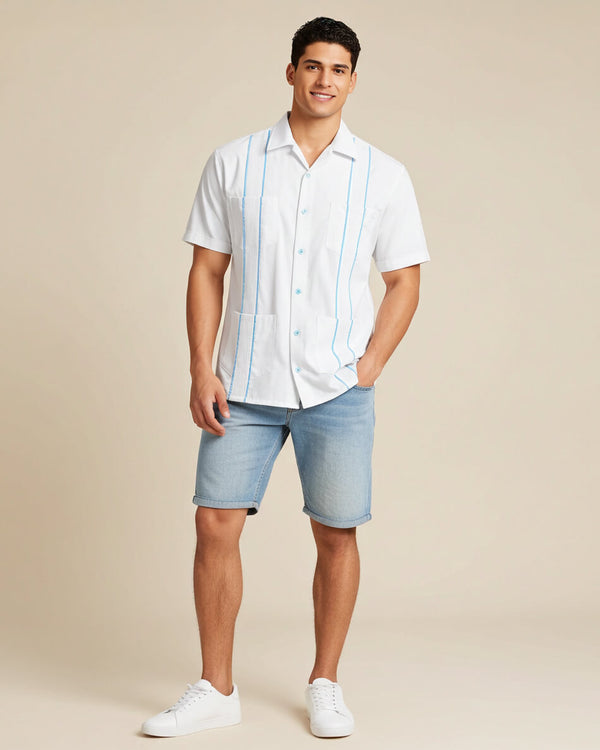 Man wearing a white guayabera short-sleeve shirt with sky blue accented pleats and light blue shorts on a beige background