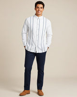 Man wearing a white shirt with navy gingham fabric accents and navy pants on a beige background