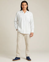 Person wearing a white guayabera shirt and beige pants against a plain background