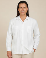 Man wearing a white button-up guayabera shirt against a beige background