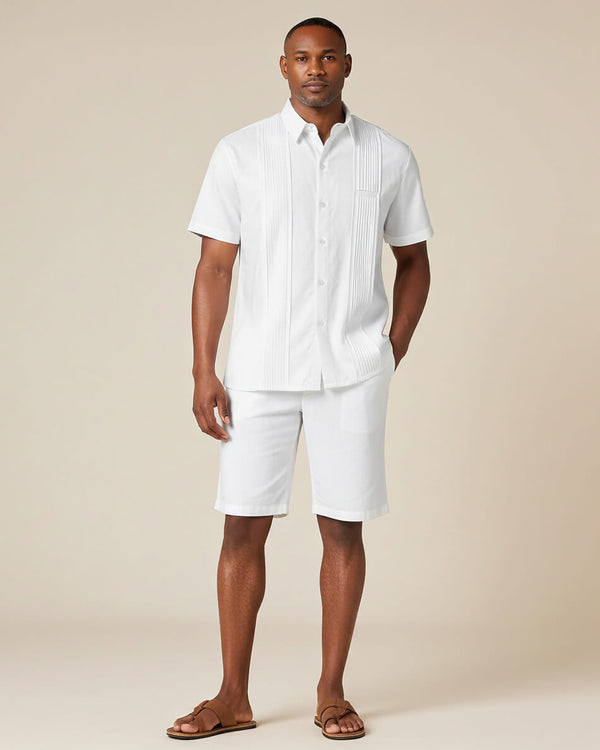 Man wearing a white guayabera short-sleeve shirt and shorts on a beige background