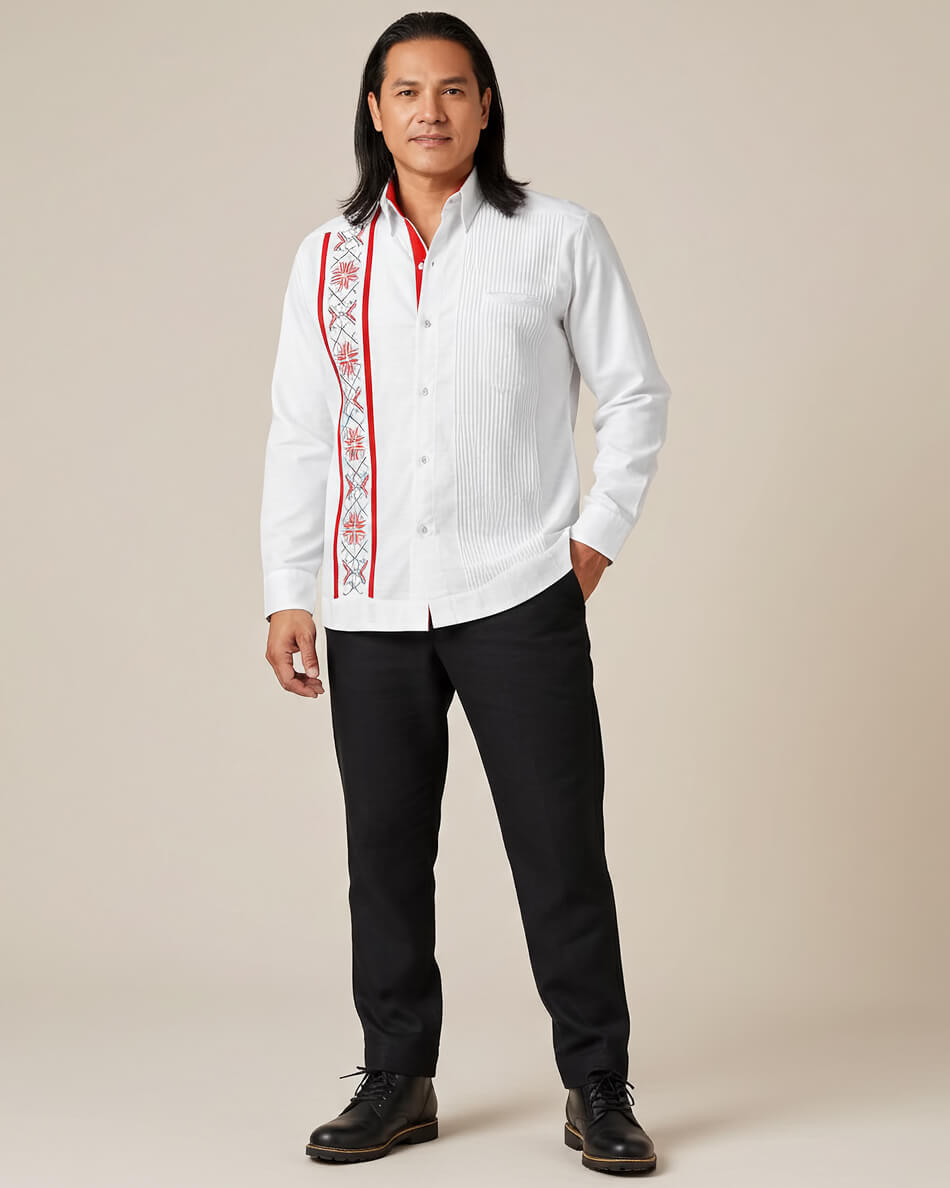 Man wearing a white guayabera red embroidered shirt with black pants on a beige background