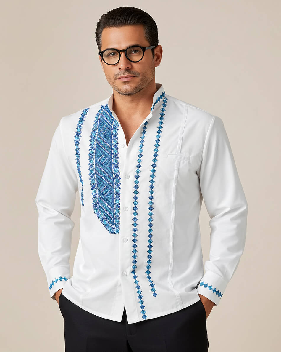 Man wearing a white guayabera shirt with blue embroidery on a beige background