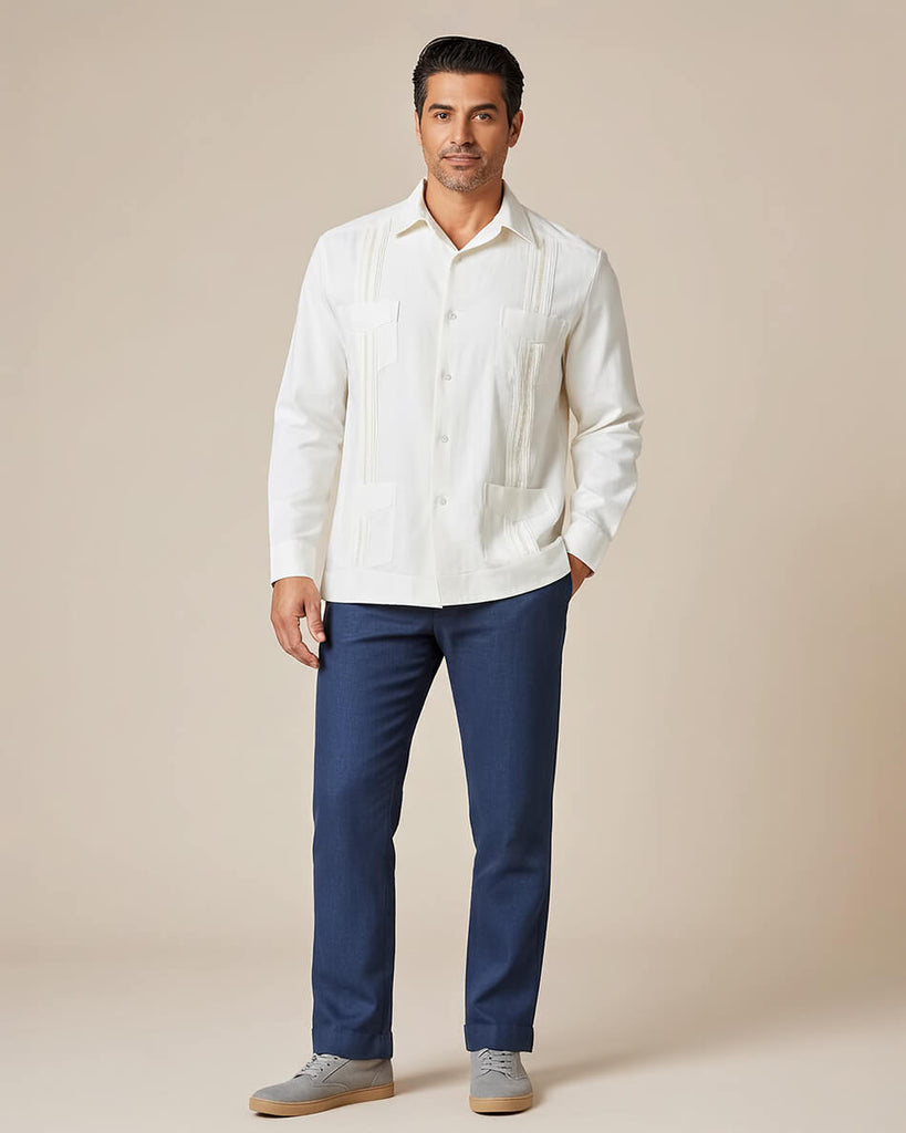 Man wearing a white guayabera shirt and blue pants against a beige background
