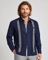 Man wearing a navy blue guayabera shirt with colorful embroidery on a light gray background