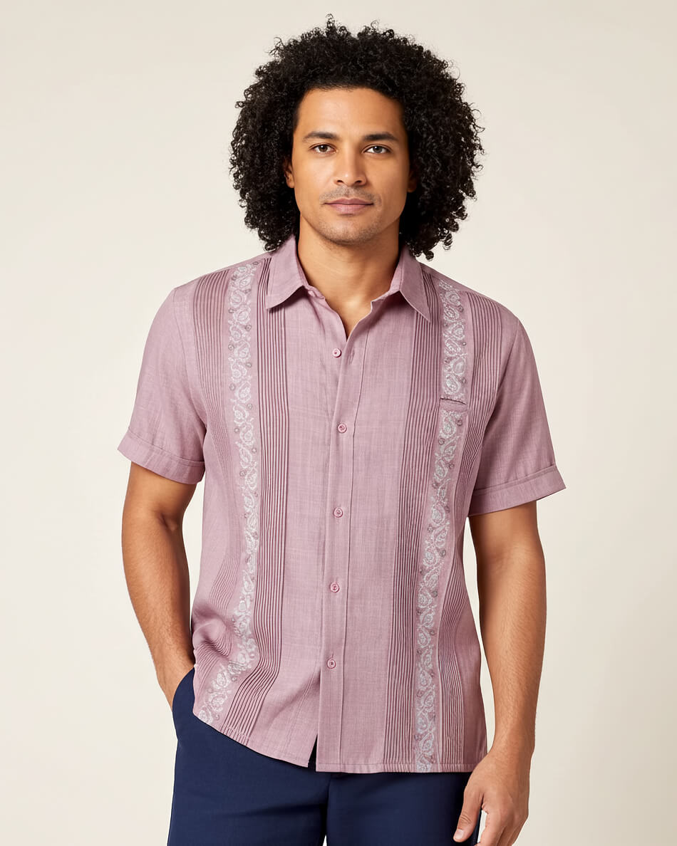 Man wearing a patterned pink guayabera shirt with white embroidery on a beige background