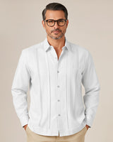 Man wearing a white button-up guayabera shirt with a subtle pattern on a beige background