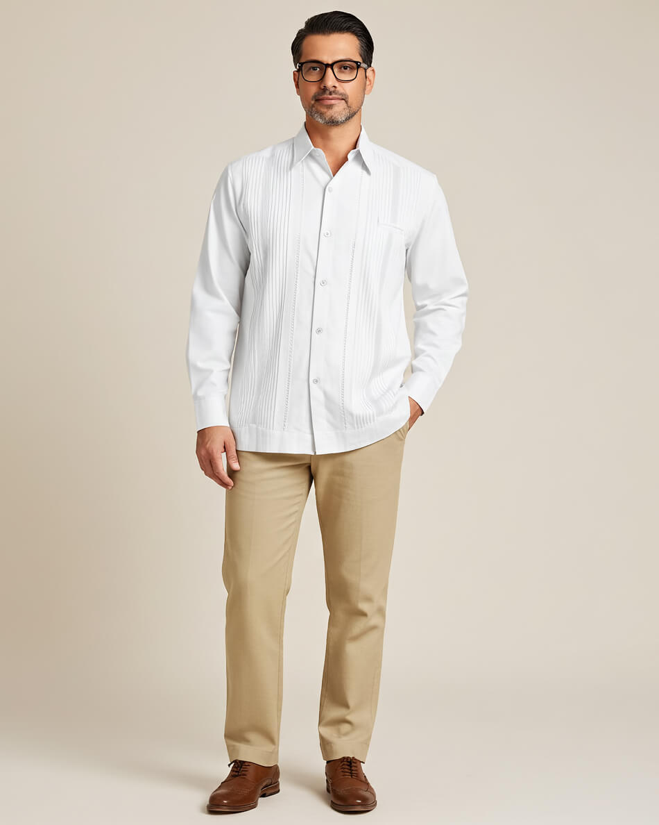 Man wearing a white guayabera button-up shirt, beige pants, and brown shoes against a beige background