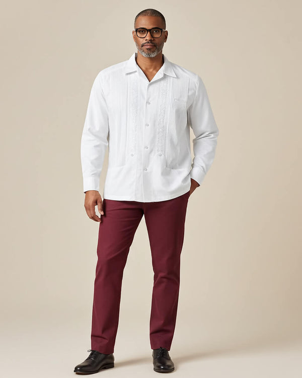 Man wearing a white guayabera shirt and maroon pants against a beige background