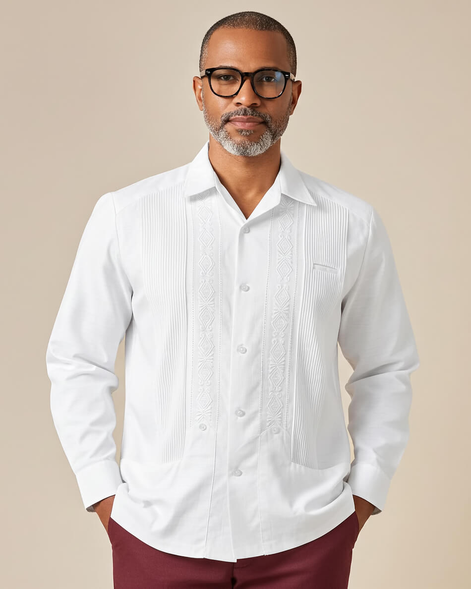 Man wearing a white nortena guayabera shirt and maroon pants against a beige background