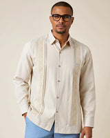 Man wearing a beige embroidered guayabera shirt with a plain background