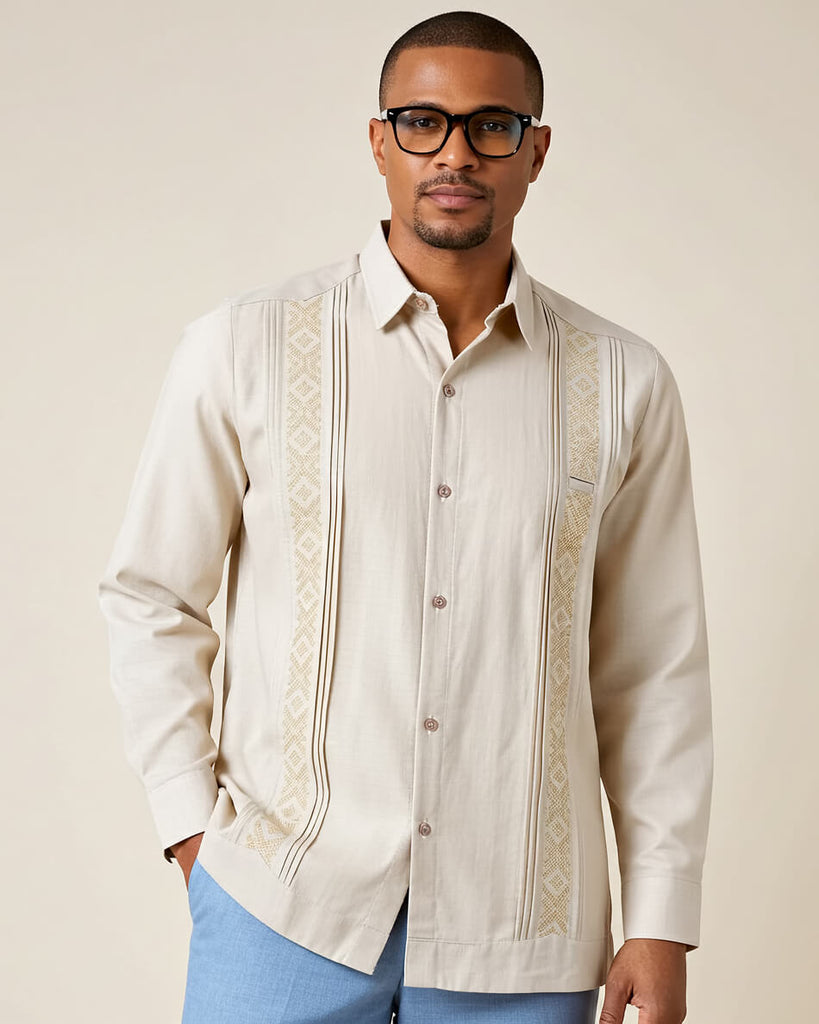 Man wearing a beige embroidered guayabera shirt with a plain background