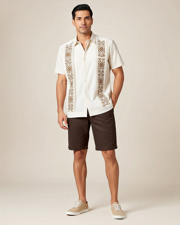 Man wearing a beige guayabera embroidered shirt with brown shorts on a beige background