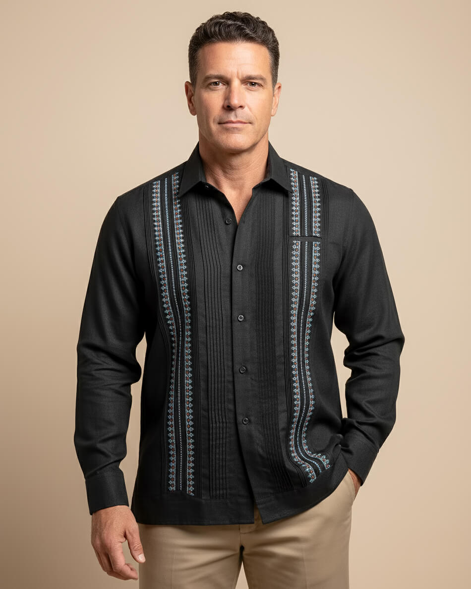 Man wearing a black embroidered guayabera shirt against a beige background
