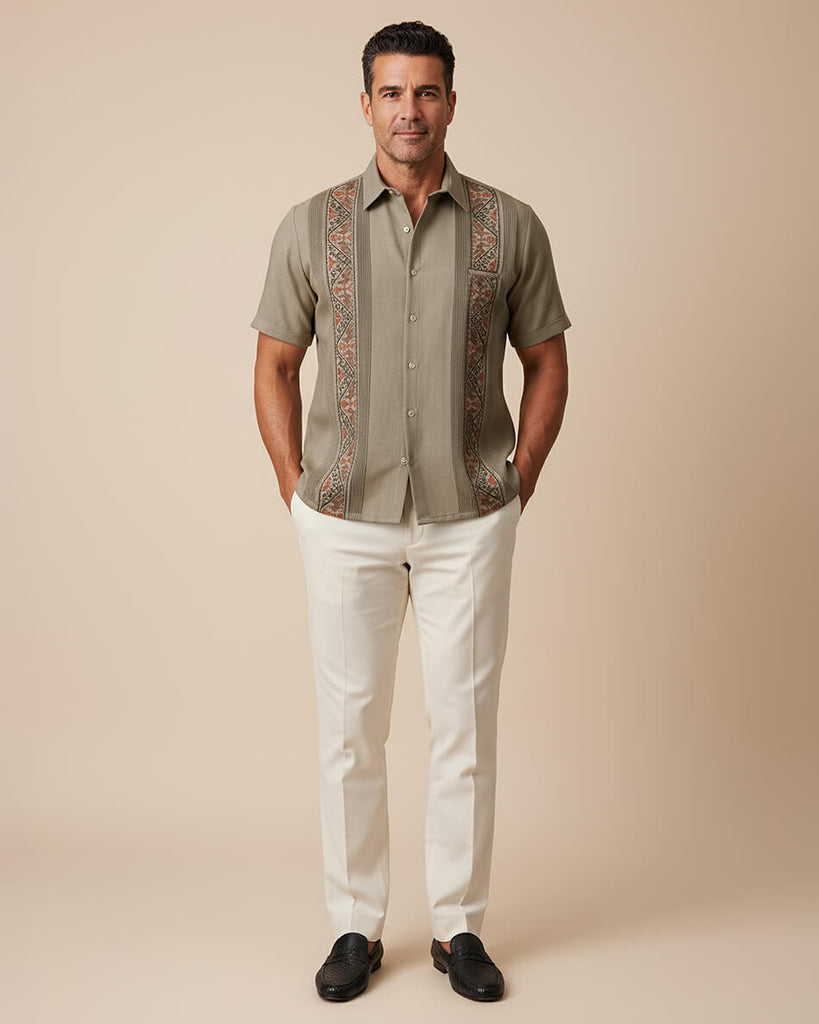 Man wearing a patterned khaki guayabera shirt with tan pants on a beige background