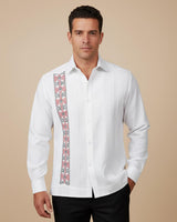 Man wearing a white guayabera dress shirt with colorful embroidery on a beige background