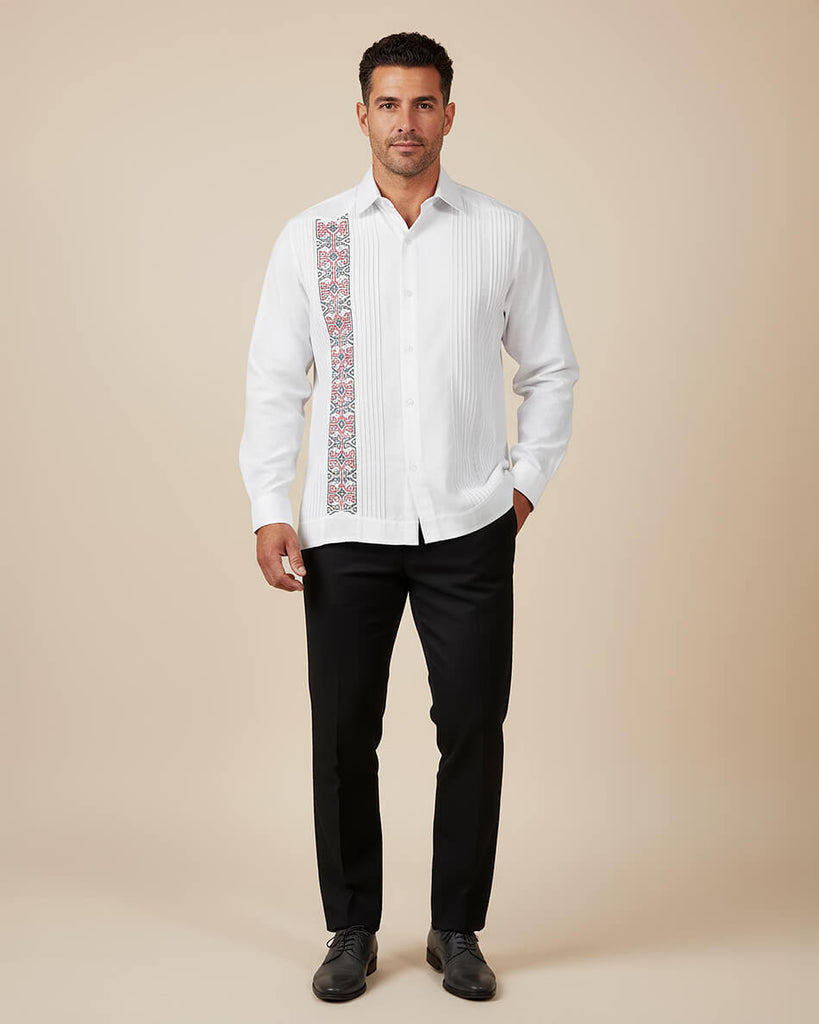 Man wearing a white embroidered guayabera shirt with black pants on a beige background