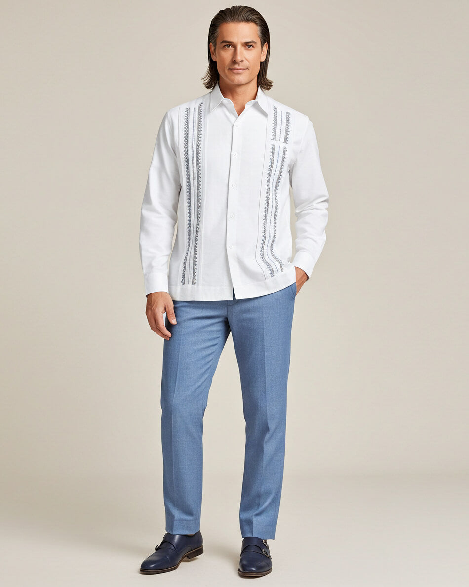 Man wearing a white guayabera embroidered shirt and blue pants on a beige background