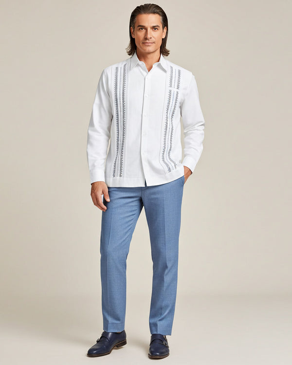 Man wearing a white guayabera embroidered shirt and blue pants on a beige background