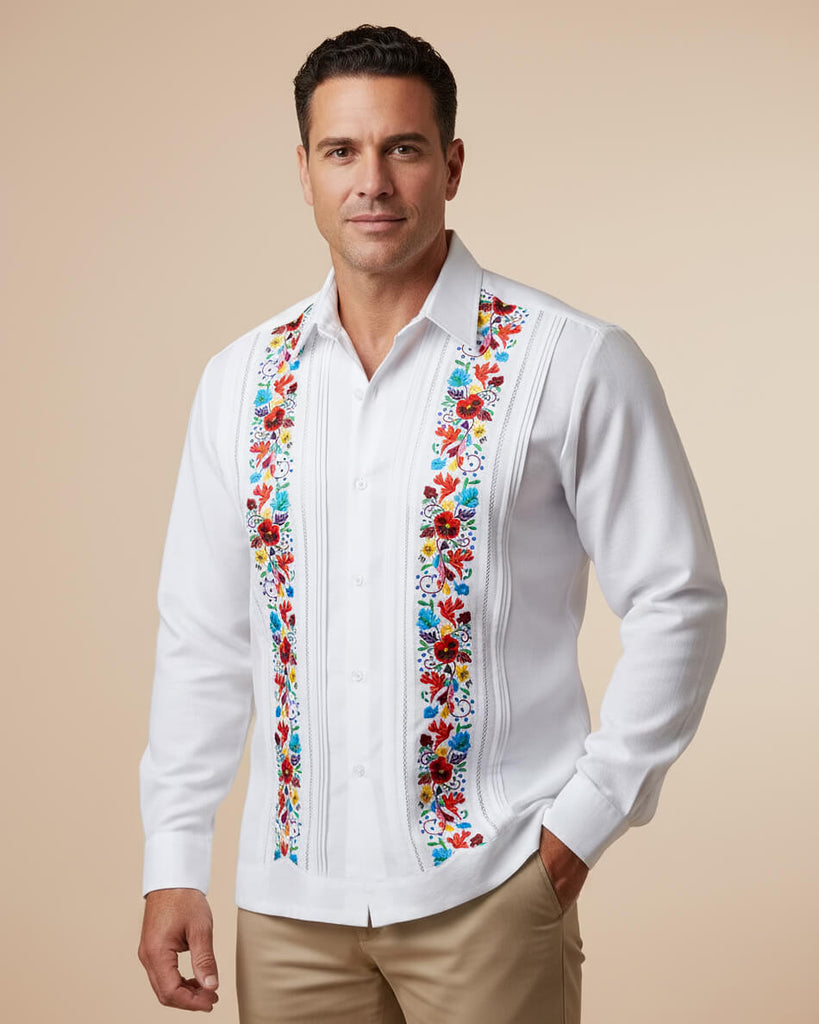 Man wearing a white guayabera shirt with colorful floral embroidery on a beige background