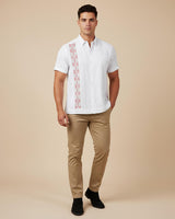 Man wearing a white guayabera embroidered shirt and beige pants on a beige background