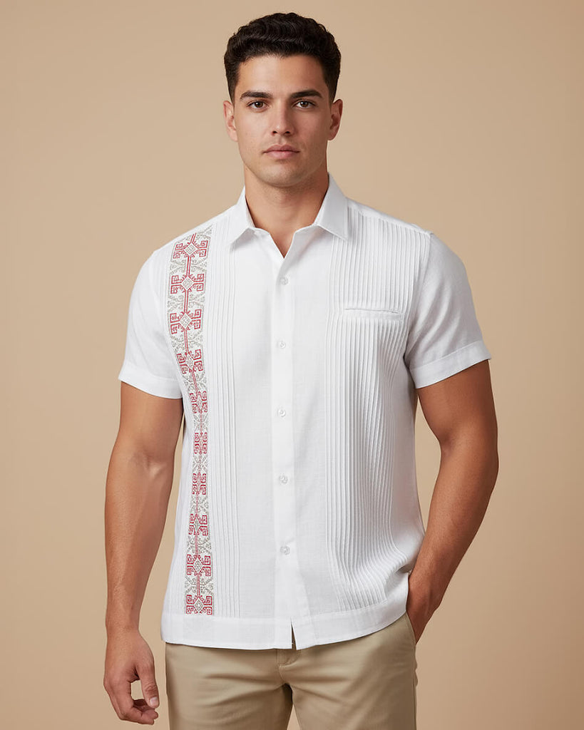 Man wearing a white guayabera short-sleeve shirt with red embroidery on a beige background