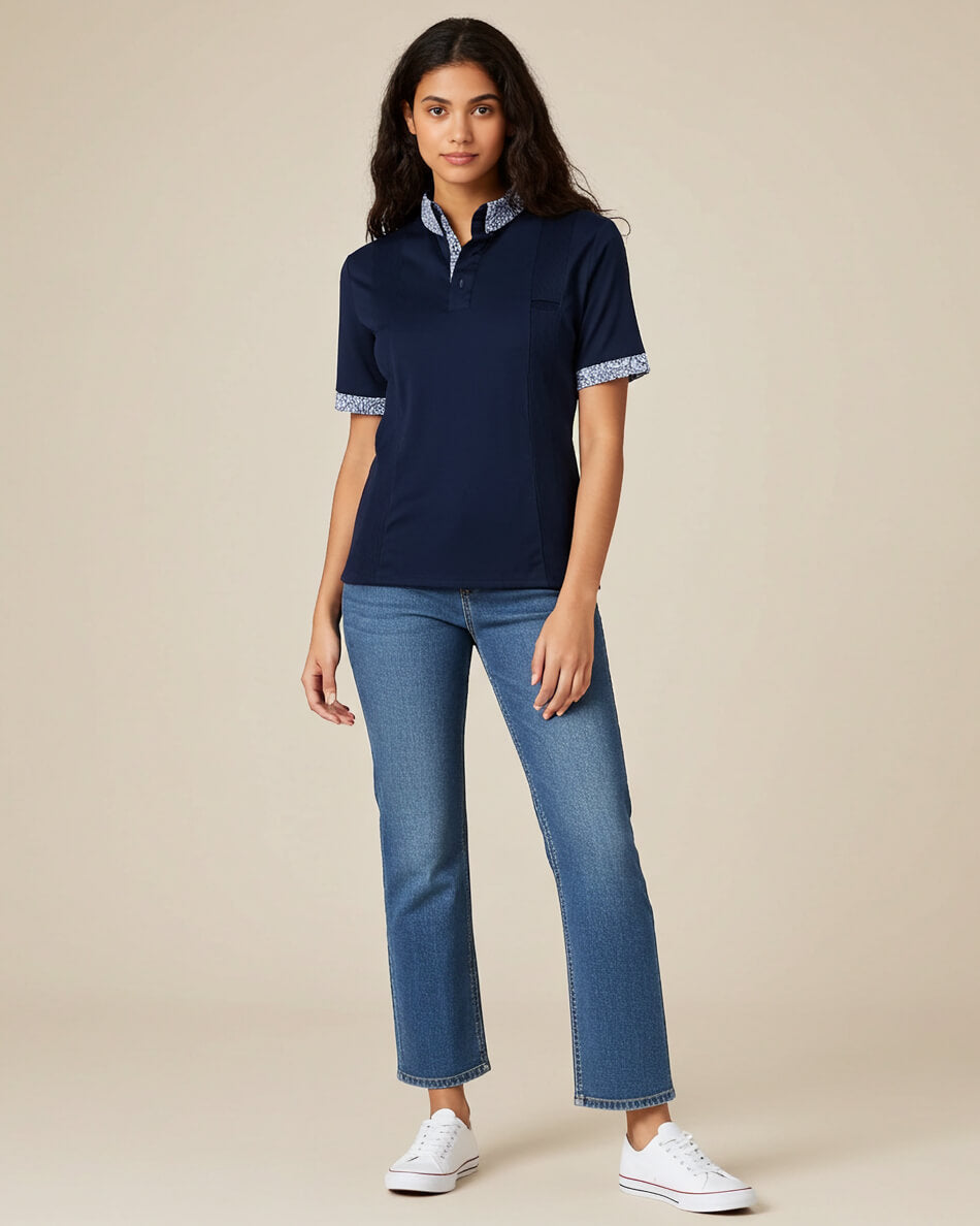 Woman wearing a navy blue polo shirt and jeans on a beige background